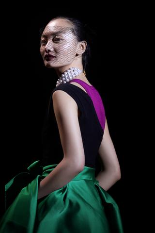 A woman model in black purple top and dark green skirt