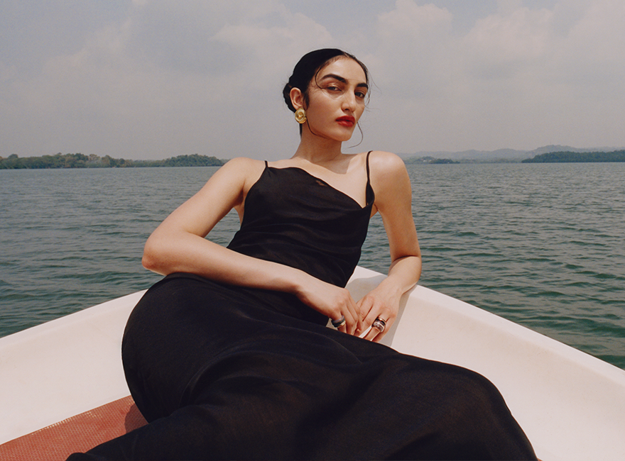 Model seating in a boat wearing a long black dress