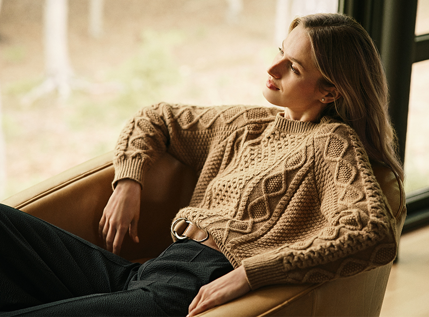 A woman in a sweater siting on a chair