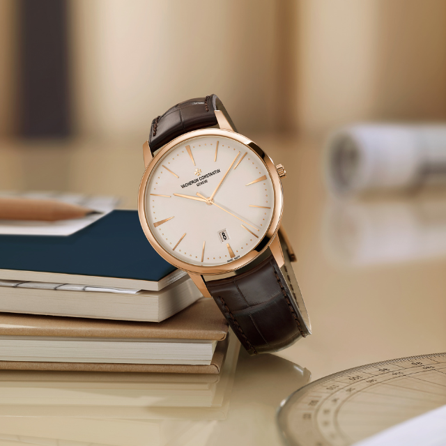 A watch with a white shield, golden case and a leather strap in dark brown